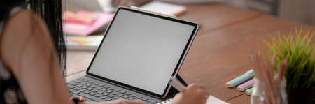 Cropped shot of female university student taking short note while looking information on blank...
