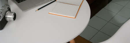 Cropped shot of portable workspace with camera, stationery, notebook and copy space on white circle...
