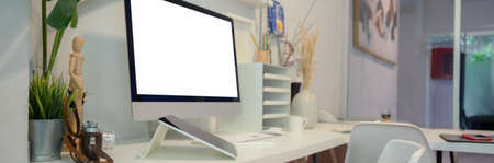 Cropped shot of comfortable office desk with blank screen computer, tablet and office supplies on...