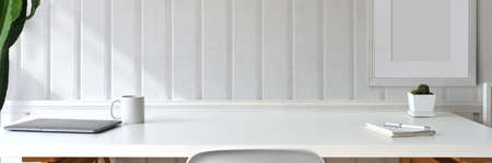 Close up view of minimal workspace with laptop, supplies, coffee cup, decoration and copy space on...