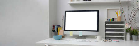 Cropped shot of of simple office desk with blank screen computer, office supplies and decorations on...