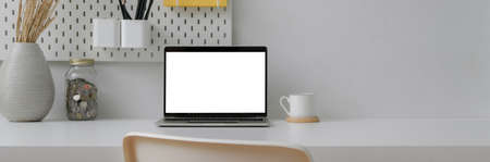 Close up view of home office with blank screen laptop, decorations and copy space on white table