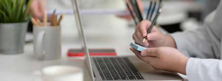 Side view of businesswoman taking short note on note pad while searching information on laptop in...