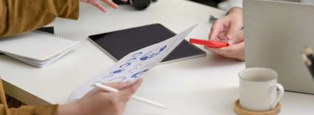 Cropped shot of start up partners working together on white table with digital devices and paper...