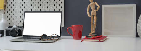 Close up view of office desk with mock-up laptop, decorations and office supplies on white table...