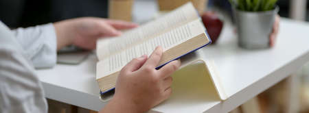 Cropped shot of female university student reading a book to prepare upcoming exam