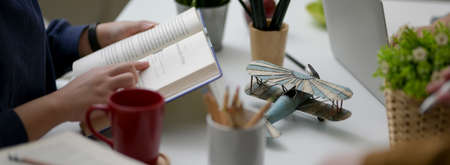 Side view of female college student looking for information on a book while doing her assignment on...