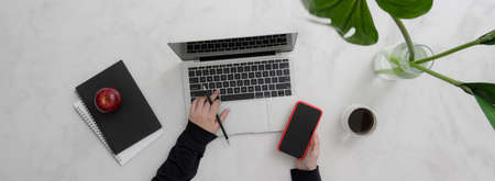 Overhead shot of female entrepreneur work from home with laptop, smartphone and notebooks in modern workspaceの写真素材