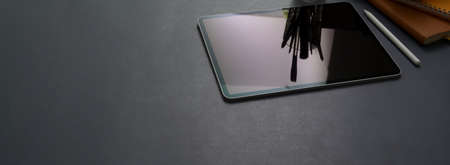 Cropped shot of dark concept office desk with digital tablet, stylus pen, office supplies and copy...