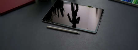 Cropped shot of dark concept office desk with digital tablet, stylus pen and office supplies on...