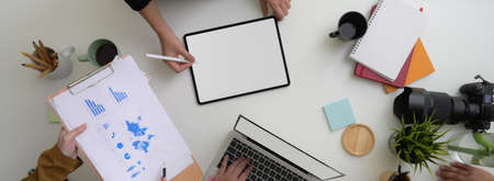 Top view of start up business team discussing on their project with digital devices and paperwork in minimal meeting roomの写真素材