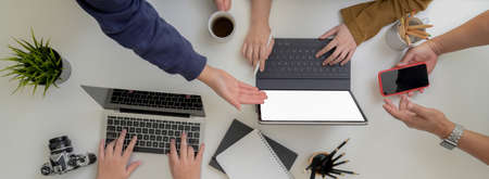 Top view of start up business team brainstorming on their project in minimal workspace with digital device and office suppliesの写真素材