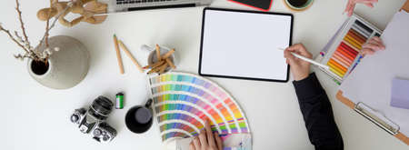 Overhead shot of designer working on mock-up digital tablet, designer supplies and decorations at comfortable workspaceの写真素材