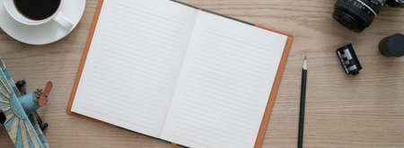 Overhead shot of comfortable workspace with open blank notebook, coffee cup camera and decoration on wooden deskの写真素材