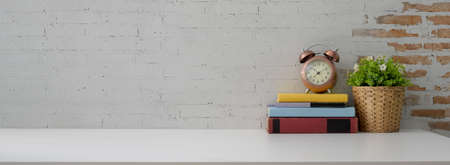 Close up view of contemporary workspace with books, decorations and copy space on white table with brick wallの写真素材