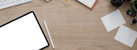 Overhead shot of comfortable workspace with blank screen tablet, supplies, camera and copy space on...