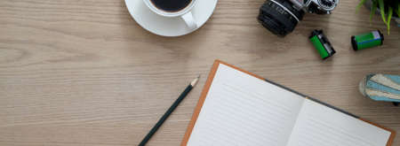 Overhead shot of comfortable workspace with open blank notebook, coffee cup camera and copy space on wooden deskの写真素材