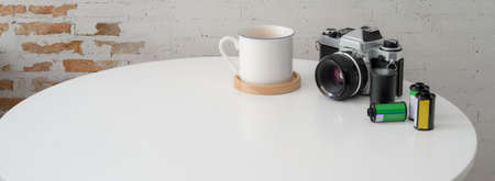 Close up view of portable workspace with camera, coffee cup and copy space on white circle table の写真素材