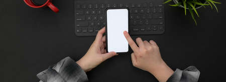 Overhead shot of female entrepreneur using blank screen smartphone to relax while working with...