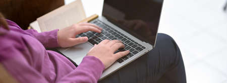 Cropped shot of young female student working on her assignment with laptop computer at her living room, work from home conceptの写真素材