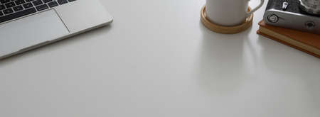 Cropped shot of modern office desk with laptop, office supplies and copy space on white table