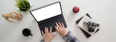 Overhead shot of freelancer working with blank screen tablet, camera and other supples on white table in minimal home officeの写真素材