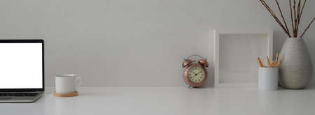 Close up view of modern workspace with mock-up laptop, decorations and copy space on white table with white wallの写真素材