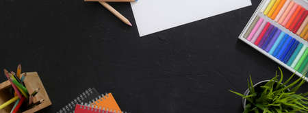 Top view of of artist workspace with sketch paper, oil pastels, painting tools and copy space on...