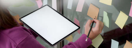 Close up view of female college student  preparing her presentation with mock-up tablet and sticky...