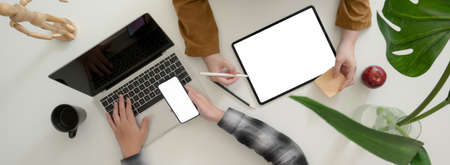 Top view of businesspeople consulting on their business strategy with mock-up digital devices on white tableの写真素材