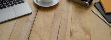 Cropped shot of modern rustic worktable with laptop, supplies, coffee cup and copy space on wooden...