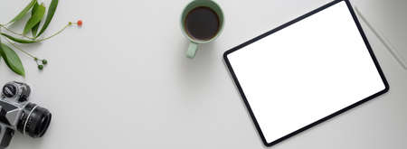 Overhead shot of modern workspace with mock-up tablet, coffee cup, camera, coffee cup and copy space on white table   の写真素材