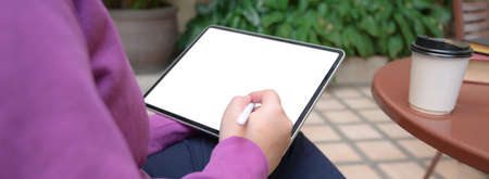 Cropped shot of female university student reading information on mock-up tablet while sitting at...