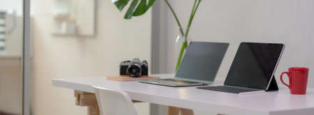 Cropped shot of comfortable office desk with laptop, digital tablet, mug, camera, office supplies...
