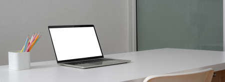 Cropped shot of simple worktable with mock-up laptop, stationery and copy space on white table in...