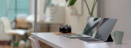 Cropped shot of comfortable office desk with laptop, digital tablet, mug, camera, office supplies...