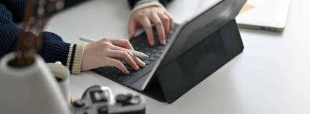 Cropped shot of female freelancer working with digital tablet on modern worktable 