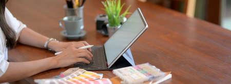 Close up view of female university student working on her project with mock-up tablet and designer...