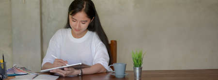 Cropped shot of female university student drawing on digital tablet while doing her project with...