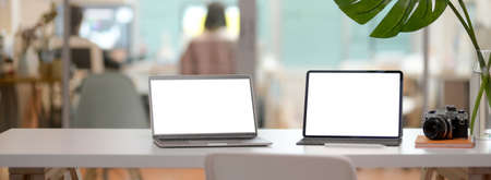 Cropped shot of comfortable office desk with mock-up laptop, tablet, camera, office supplies and...