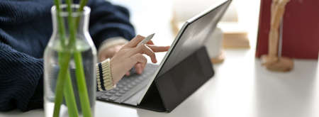 Cropped shot of female freelancer reading information on digital tablet on white worktable 