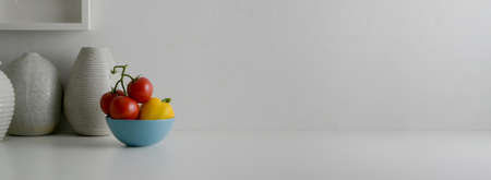 Close up view of white modern interior home designer with vegetable bowl, ceramic vases and copy space on white counter  の写真素材