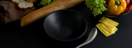 Close up view of dark modern concept kitchen table with black ceramic kitchenware, French baguette...