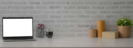 Close up view of Shipping company office desk with mock-up laptop, coffee cup, supplies, boxes and copy space on marble desk  の写真素材
