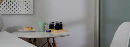 Cropped shot of coffee table with coffee mug, camera, bread and copy space on white circle desk の写真素材