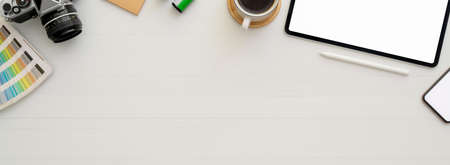 Top view of simple workspace with mock-up tablet, coffee cup, other supplies and copy space on white deskの写真素材