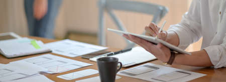 Side view of professional UI developer concentrating on his project with digital tablet and...