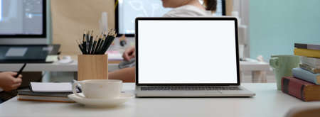 Close up view of office desk with blank screen laptop, coffee cup and stationery on white desk の写真素材
