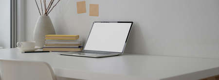 Cropped shot of portable workspace with mock-up laptop, books, decoration and copy space on white...