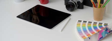 Cropped shot of photographer worktable with digital tablet, camera and colour swatch on white desk  の写真素材
